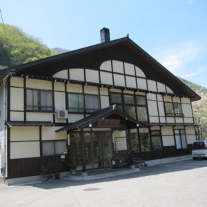 Front facade and entrance of Suisensou ryokan with wooded hillside backdrop in Gifu, Chūbu, Japan