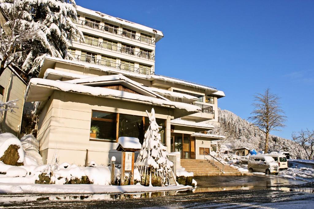 Snow covered ryokan exterior Takahan Niigata Takahan entrance and snow-covered facade with parked cars beneath a clear blue sky in Niigata