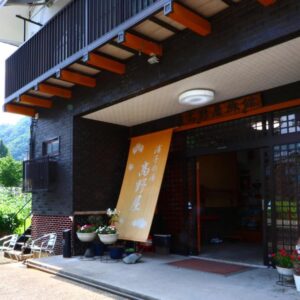 Traditional entrance with orange noren and lantern at Takanoya, Niigata, Chūbu Japan