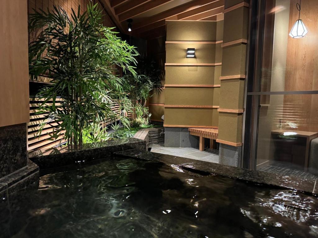 Indoor onsen at Tatsumikan Gunma Indoor stone onsen bath with plants and wooden screens at Tatsumikan in Gunma