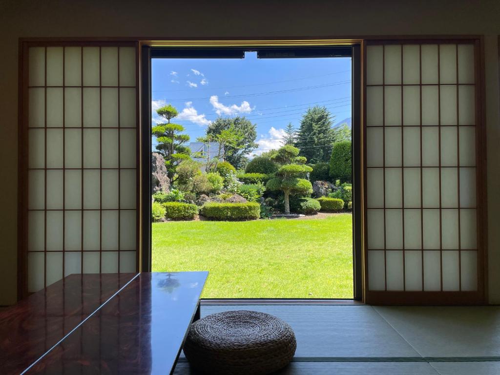 Tatami Room Garden View Togawaso Yamanashi Chubu Tatami room with shoji screens, low table and round cushion opening onto a trimmed garden under blue sky in Yamanashi