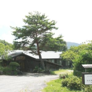 Wooden ryokan exterior with large pine tree and entrance sign at Tokonamiso in Nagano Chūbu
