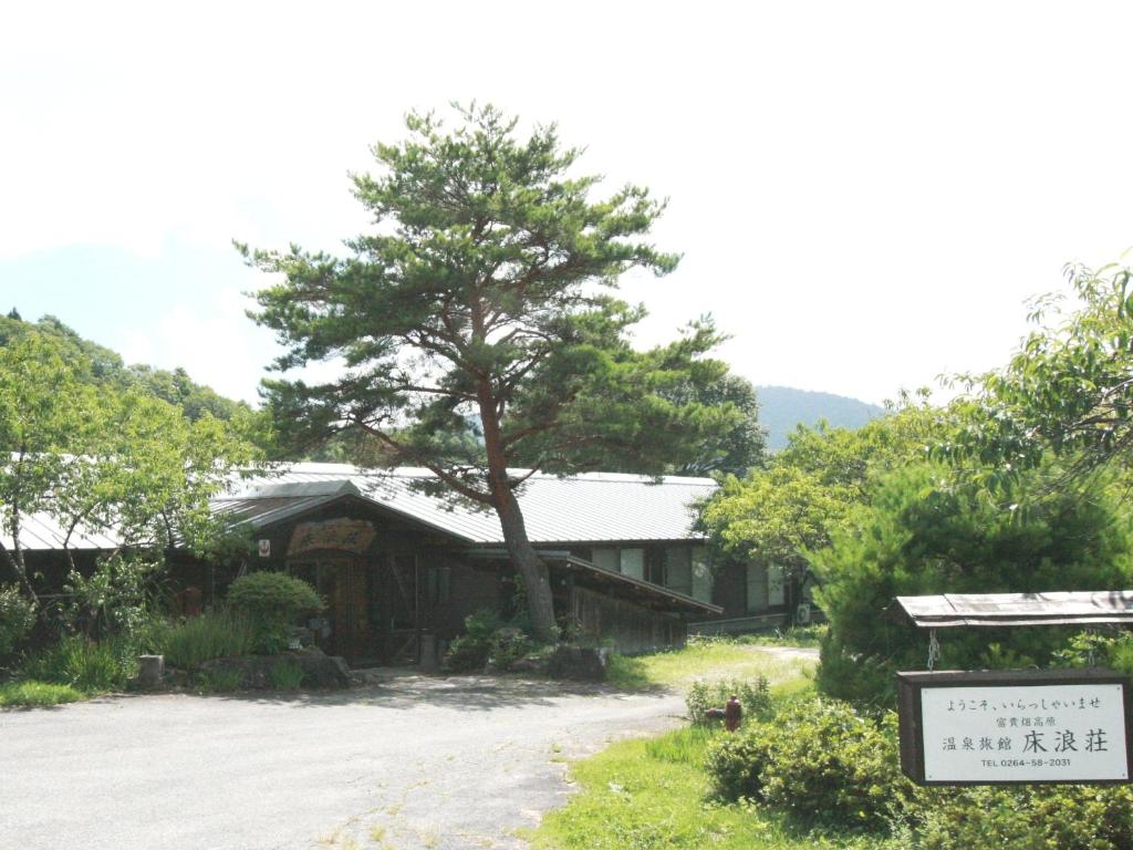 Ryokan exterior with pine Tokonamiso Nagano Wooden ryokan exterior with large pine tree and entrance sign at Tokonamiso in Nagano Chūbu