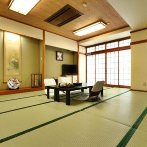 Traditional tatami room with low table, floor chairs, shoji screens and tokonoma at Toyofuku Ryokan in Hyōgo