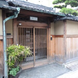 Traditional wooden entrance with sliding lattice door, potted plants and stone path at Tsubakiso, Nara, Kansai