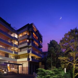 Dusk view of multi-story ryokan with lit balconies and landscaped trees at Tsuganoki in Tochigi