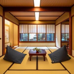 Traditional tatami room with low table, floor cushions, shoji screens and garden view at UTAIMACHI ryokan in Ishikawa