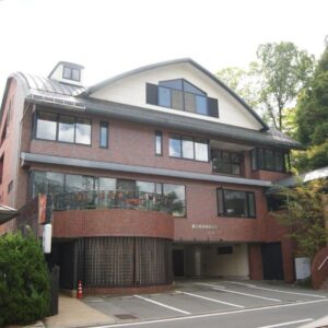 Brick exterior of Wakamizusou with covered parking and hillside greenery in Yamanashi, Chūbu