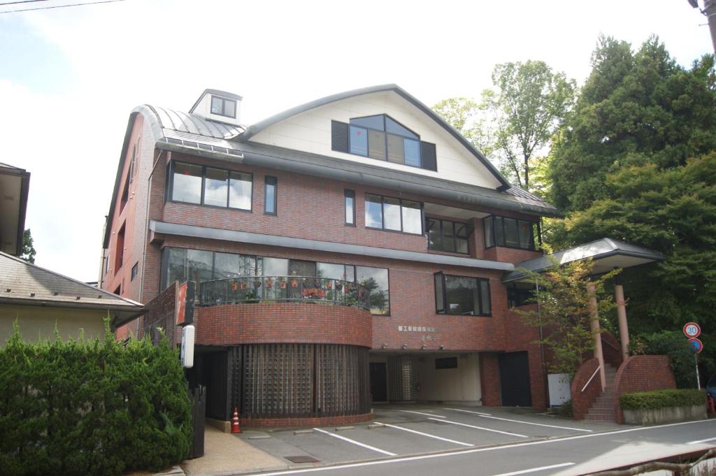 Exterior of Wakamizusou Ryokan in Yamanashi Brick exterior of Wakamizusou with covered parking and hillside greenery in Yamanashi, Chūbu