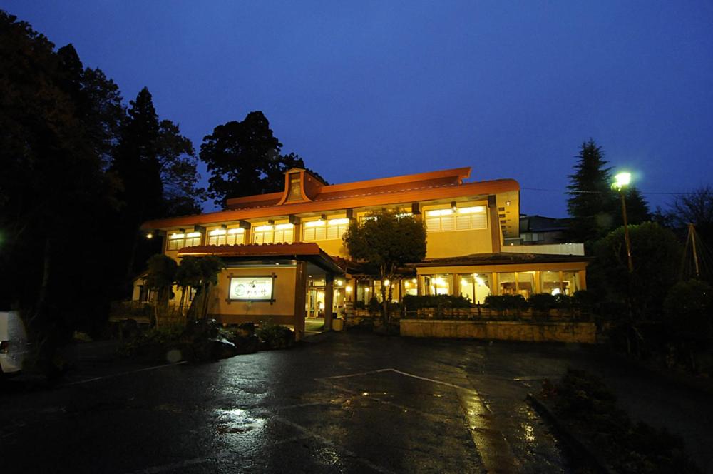 Illuminated ryokan exterior Wakatake Niigata Japan Evening exterior of Wakatake ryokan with lit facade, wet driveway and surrounding trees in Niigata, Chūbu region