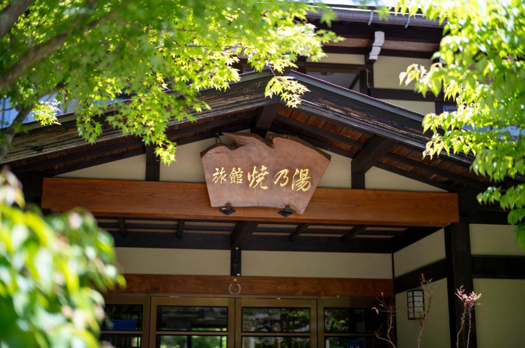 Traditional entrance Yakenoyu Chūbu Gifu Wooden ryokan entrance with carved sign and green foliage at Yakenoyu in Gifu, Chūbu