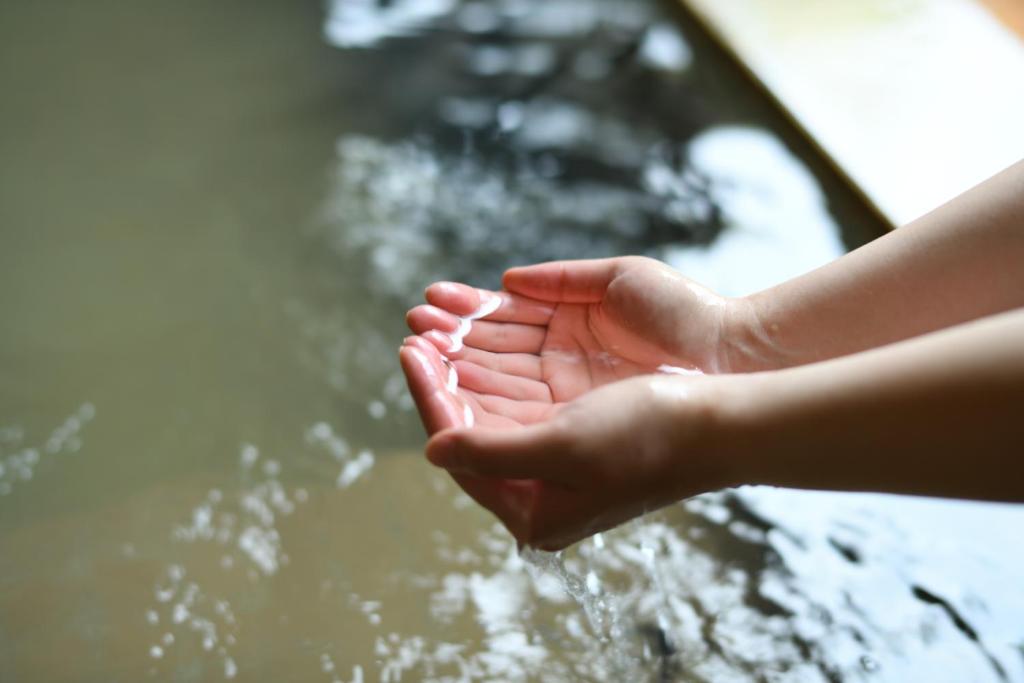 Hands in onsen at Yamagataya Fukushima Cupped hands touching warm onsen water at Yamagataya ryokan in Fukushima Tohoku