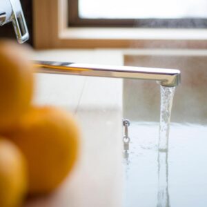 Steaming onsen faucet pouring into tub with citrus fruits nearby at Yamanoo, Ishikawa
