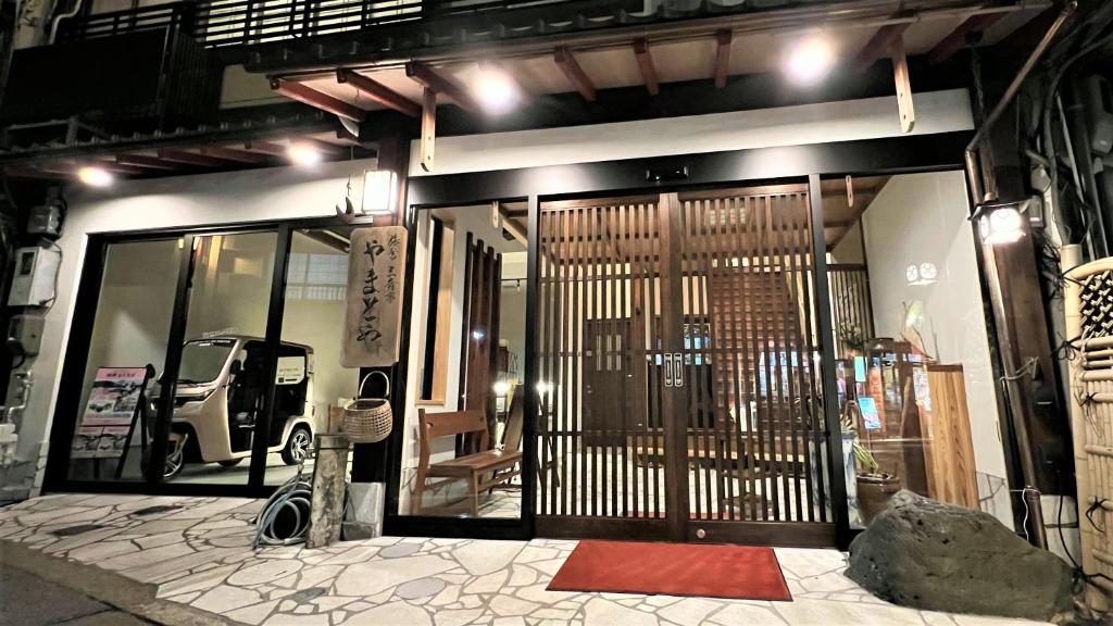 Evening ryokan entrance Yamatoya Hyōgo Nighttime entrance with wooden lattice doors, stone paving and warm lantern lighting at Yamatoya in Hyōgo, Kansai
