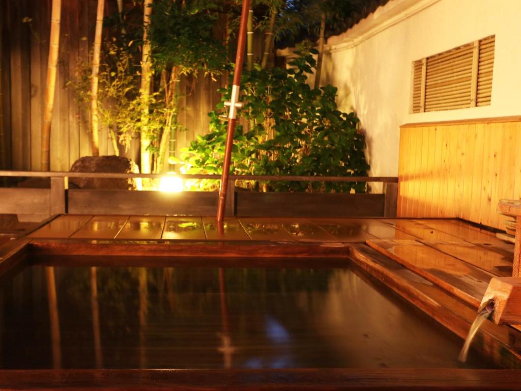 Wooden Onsen Bath at Yanagiya Yamanashi Wooden onsen bath with warm ambient lighting and garden foliage at Yanagiya in Yamanashi