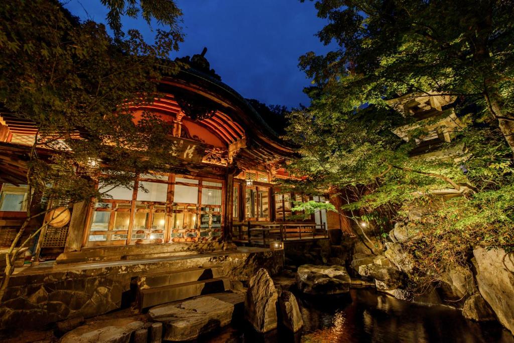 Evening garden entrance at Yorozuya Nagano Lit traditional wooden ryokan entrance with stone steps and garden pond, evening at Yorozuya in Nagano