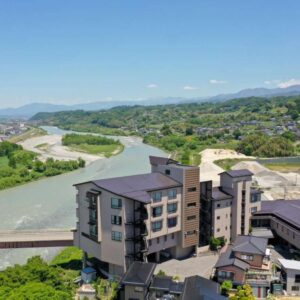 Aerial riverside view of Yoshinotei by a river and bridge with distant mountains in Nagano Chūbu