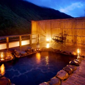 Stone outdoor onsen on wooden deck with lanterns at Yukimurasaki in Gifu Chūbu Japan