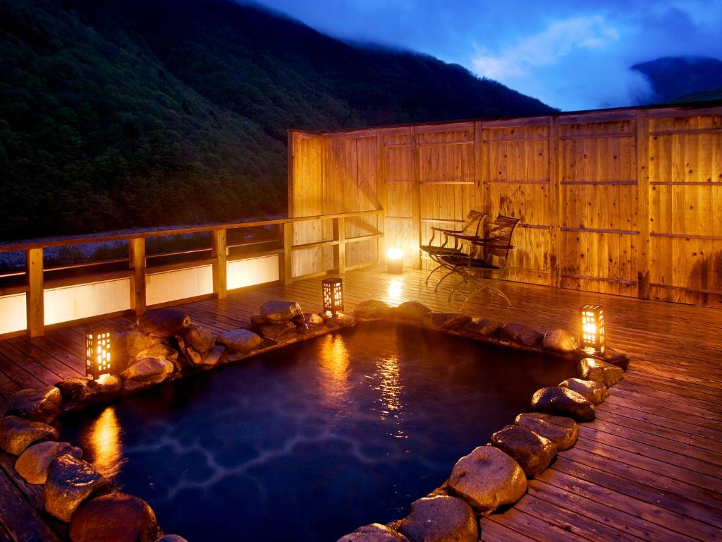 Outdoor onsen at Yukimurasaki Gifu Stone outdoor onsen on wooden deck with lanterns at Yukimurasaki in Gifu Chūbu Japan