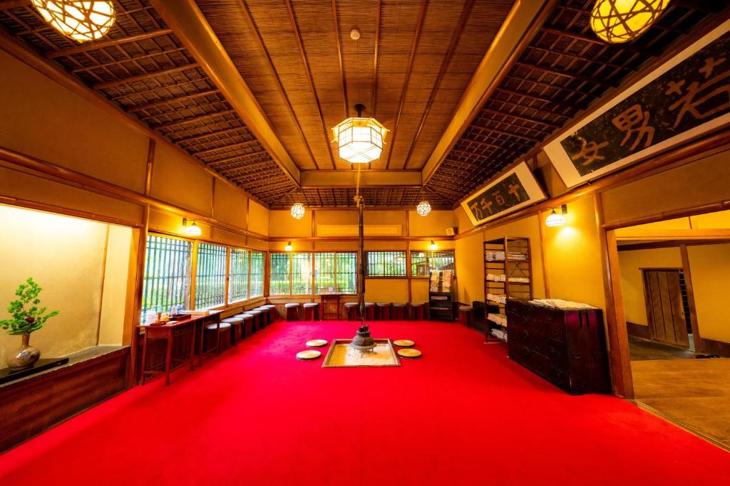 Red Carpet Communal Hall Yunoshimakan Gifu Spacious communal hall with red carpet, sunken hearth, wooden ceiling and shoji windows at Yunoshimakan, Gifu