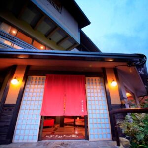 Dusk entrance with red noren and shoji screens at Yutorelo-an in Kanagawa