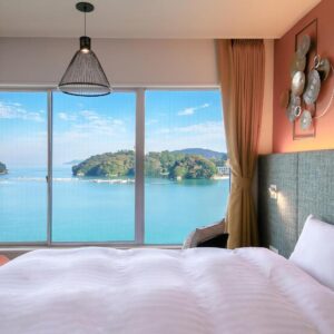 Bed by floor-to-ceiling window overlooking sea and islands at Oyado Andon Toba, Mie, Kansai