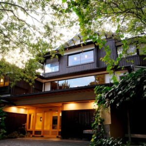 Evening view of Sanpei-sō entrance framed by trees and warm exterior lighting