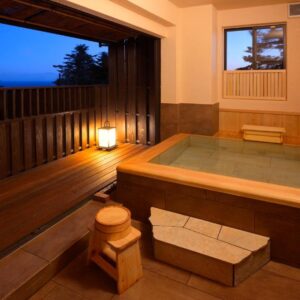 Indoor wooden onsen bath with wooden railing and dusk sky at 伊豆高原の隠れ宿Syuhari守破離, Shizuoka