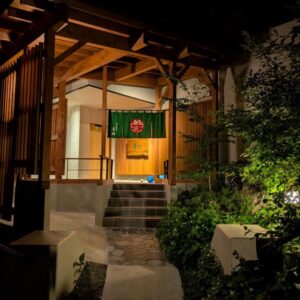 Wooden ryokan entrance with green noren and stone steps at Shinobu Onsen Seishū, Fukushima