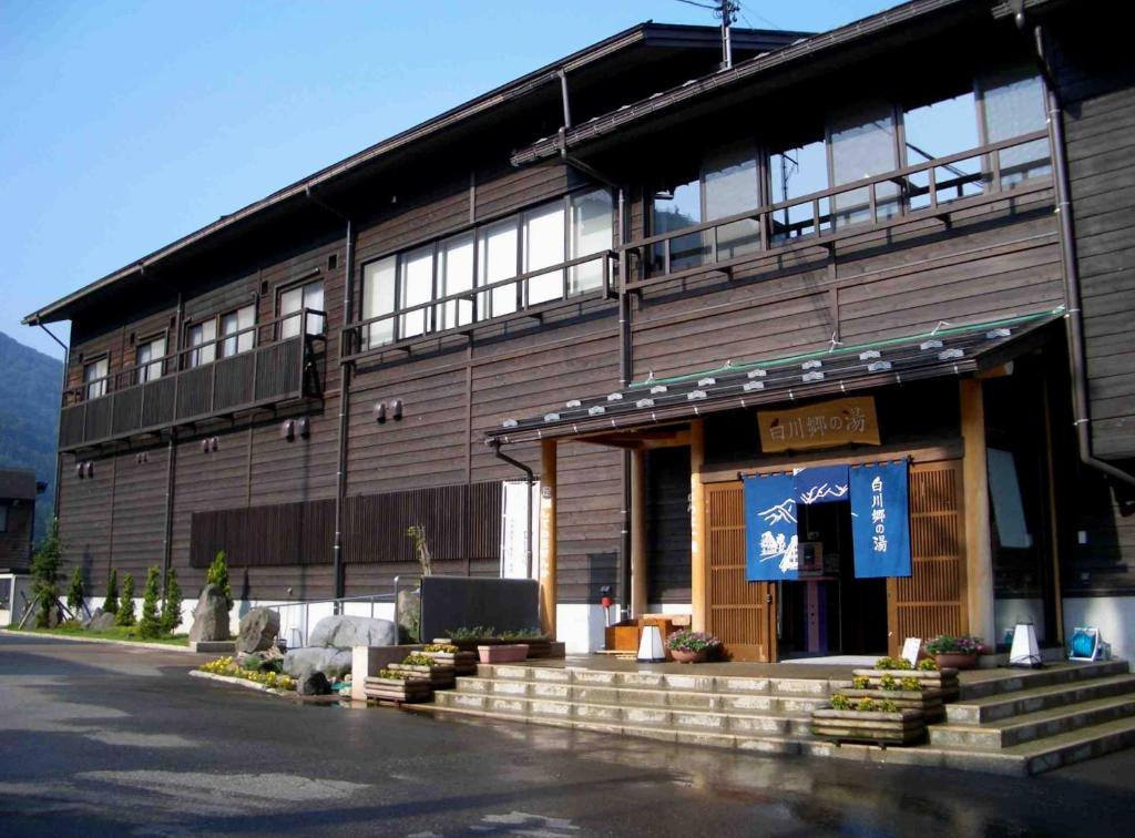Traditional wooden ryokan Shirakawagō no Yu Gifu Wooden two-story ryokan exterior with blue noren and stone steps, Shirakawagō no Yu, Gifu