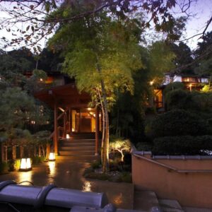 Evening view of illuminated wooden entrance, stone steps and lanterns at Yama no Chaya in Kanagawa