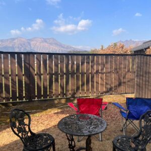 Outdoor terrace with metal table, folding chairs and wooden fence at Oyado Daikonya in Kumamoto, Kyushu