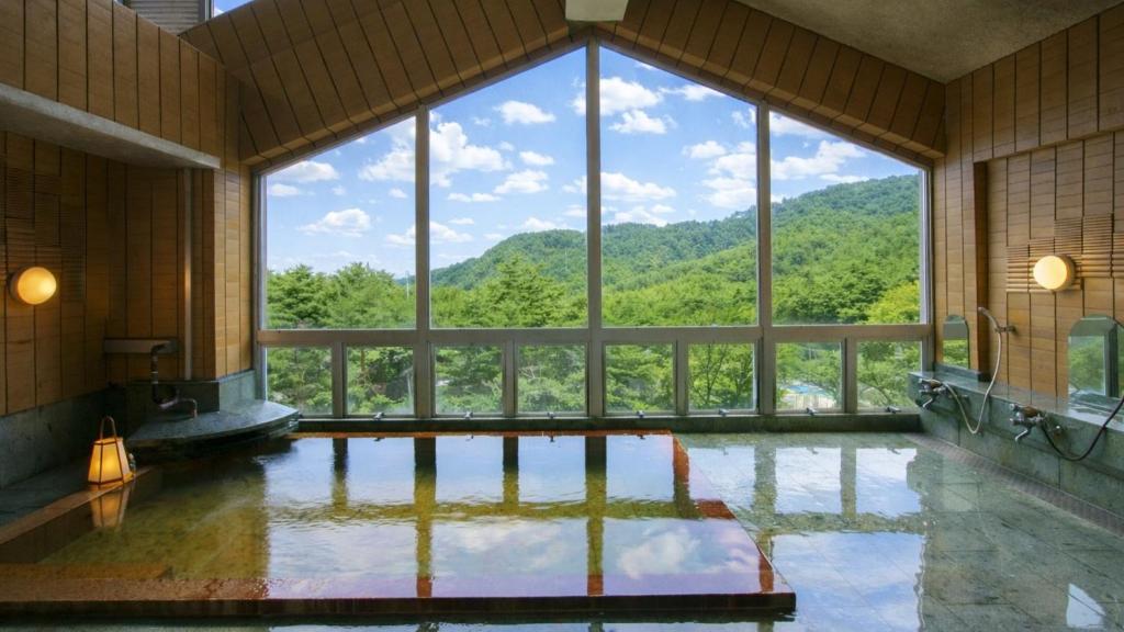 Indoor Onsen Bath Matsutake Sansō Nagano Spacious indoor onsen bath with floor-to-ceiling windows and forested mountain views at Matsutake Sansō, Nagano