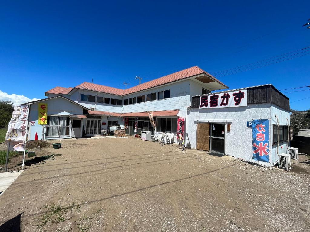 Exterior of Minshuku Kazu in Chiba Two-story Minshuku Kazu exterior with banners and gravel courtyard under clear blue sky, Chiba Kantō
