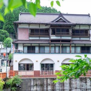 Three-story riverside ryokan with wooden balconies and lush hillside backdrop in Dorogawa, Nara, Kansai, Japan