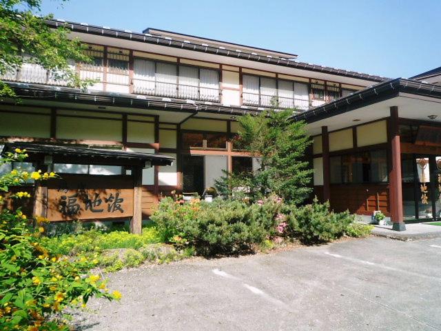 Traditional ryokan entrance Yushō Fukujikan Gifu Two-story traditional ryokan facade with wooden entrance, signboard and surrounding greenery at Yushō Fukujikan, Gifu