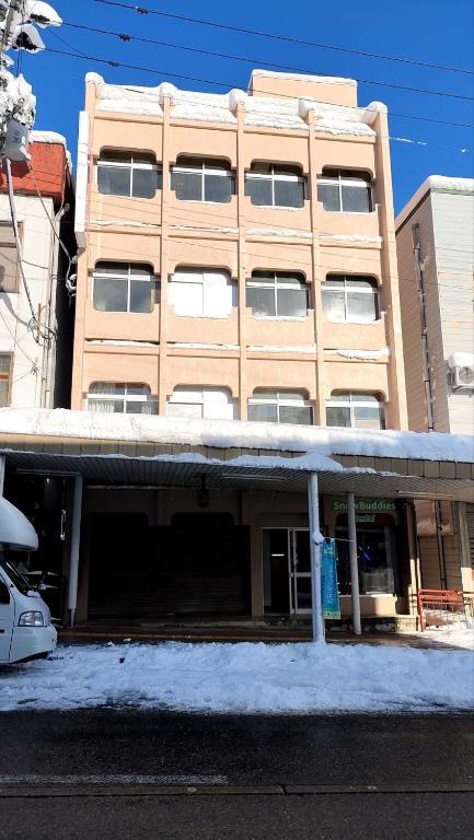 Snow-covered Auberge de poudreuse de Yuzawa Niigata Exterior of multi-story ryokan with snow-covered roof and bus in front at Auberge de poudreuse de Yuzawa, Niigata