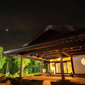 Wooden entrance and lit interior under a starry sky at Kamikura, Matsurube Onsen, Iwate