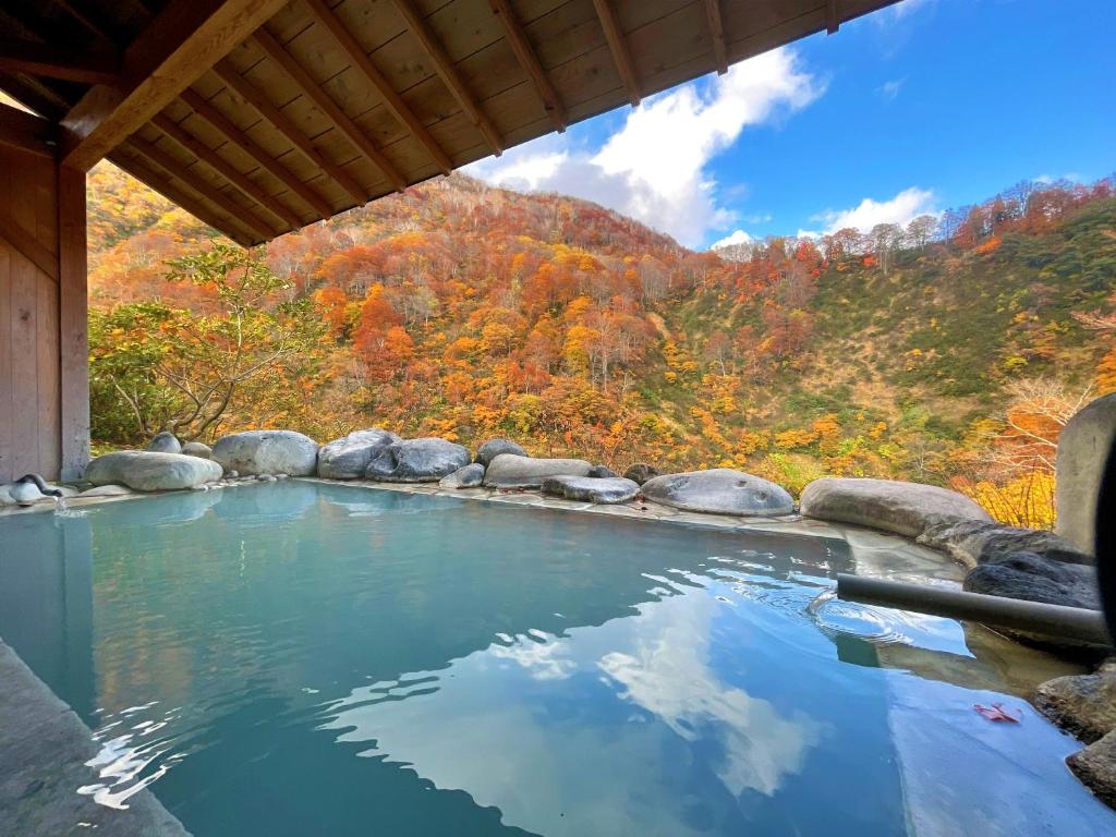 Autumn open-air onsen at Hitō Hanabun Niigata Outdoor stone onsen reflecting sky and autumn foliage, Hitō Hanabun, Niigata, Chūbu, Japan