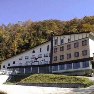 Three-story lodge on wooded hillside with driveway and balconies at Naeba Lodge Oka, Niigata